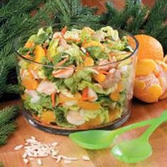 a glass bowl filled with salad next to oranges