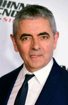 a man in a suit and tie posing for a photo on the red carpet at an event