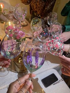 several people holding up wine glasses with flowers on them