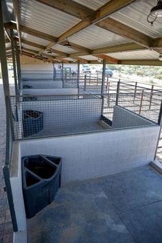 the inside of a building with several cages and trash cans on it's sides