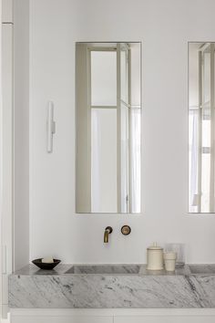 a bathroom with marble counter tops and two mirrors on the wall, one above the sink