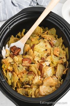 a close up of food in a crock pot with a wooden spoon on the side