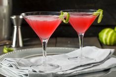 two martinis with lime garnish sit on a plate