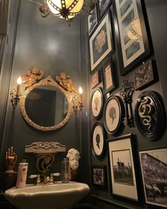 a bathroom with pictures on the wall and a sink in front of an ornate mirror