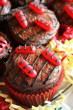 some cupcakes with chocolate frosting and red decorations