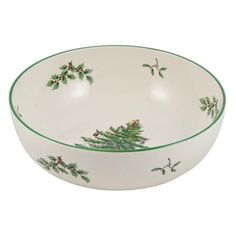 a white bowl with green trimmings and holly branches on the rim, sitting in front of a white background