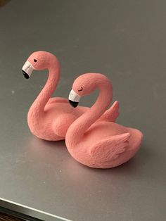 two pink flamingos sitting on top of a table