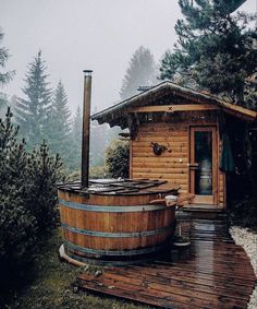 a wooden hot tub sitting on top of a wooden deck next to a tree filled forest