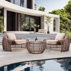 wicker furniture sitting on the edge of a pool in front of a modern house