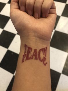 a person's arm with the word peace tattooed on it, in front of a black and white checkered floor