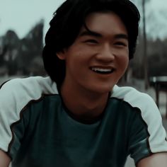 a young man smiling and wearing a green shirt