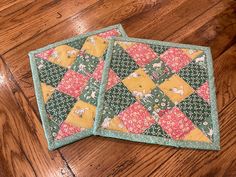 two quilted coasters sitting on top of a wooden floor