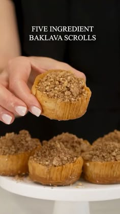 a close up of a person holding a pastry in front of other muffins