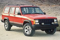 a red jeep is parked in the desert