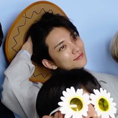 a man and woman holding flowers in front of their faces while they look at the camera