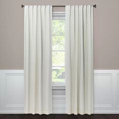 a white curtain hanging on the side of a window in a room with hardwood floors