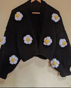 a black sweater with white and yellow flowers on it