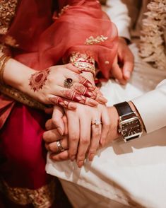 two people holding each other's hands while wearing wedding rings and bracelets on their fingers