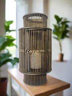 a birdcage sitting on top of a wooden table next to a potted plant