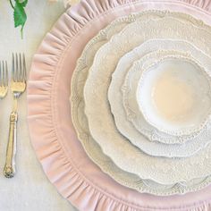 there is a pink plate and silverware set on the white tablecloth with roses