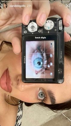 a woman holding up a camera to take a photo with an eyeball on it