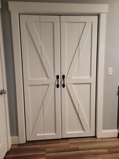 two white double doors in a room with hardwood floors