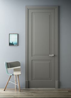 a chair sitting in front of a gray door with a frame on the wall next to it