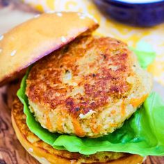 a close up of a burger on a wooden board with lettuce and cheese