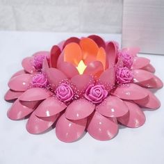 a pink flower candle holder sitting on top of a white table next to a wall