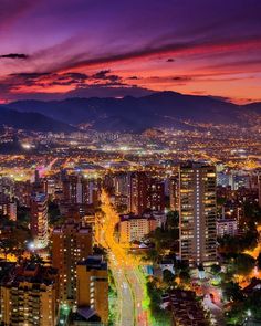 an aerial view of a city at night with lights on and mountains in the background