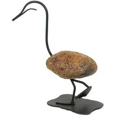 a metal sculpture of a bird with a long neck and legs, standing on a black base