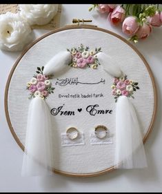 two white doves with pink flowers on their heads are sitting in front of a wedding ring and veil