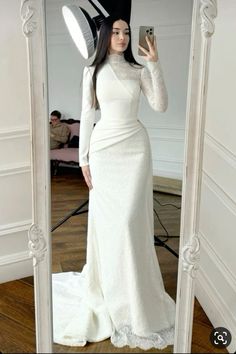 a woman is taking a selfie in a mirror wearing a white dress and black hat