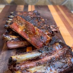 some ribs are on a cutting board with sauce and seasoning sprinkles