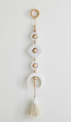 a white wall hanging with three wooden circles and two tassels on the end