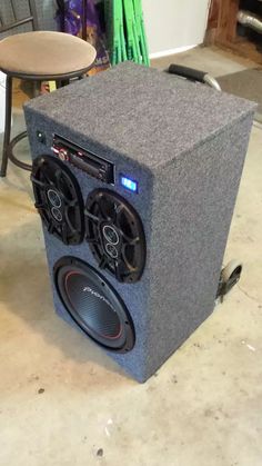 a large speaker sitting on top of a floor next to a chair