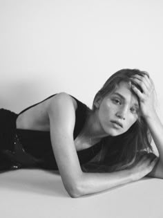 black and white photograph of a woman laying on the floor with her hands behind her head