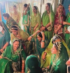 a group of women dressed in green and yellow saris posing for a photo together