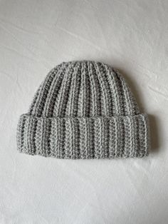 a gray knitted hat laying on top of a white sheet