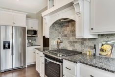 a kitchen with white cabinets and granite counter tops, stainless steel appliances and an oven