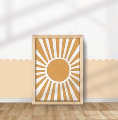 an empty room with a wooden floor and a framed sunburst on the wall