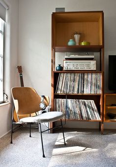 a room with a book shelf, chair and television