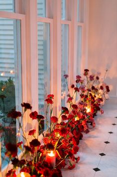 flowers and candles are lined up along the windowsill