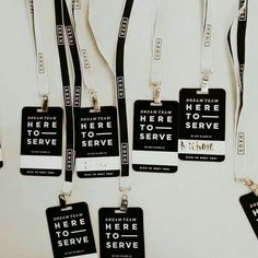 five black and white luggage tags hanging on a wall with the words here to serve