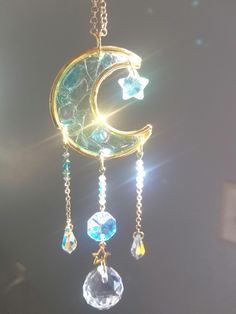 the sun shines brightly behind a crescent moon with crystals hanging from it's sides