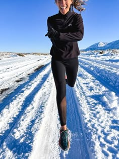 a woman running in the snow on a sunny day