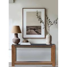 a table with two vases and a lamp on it next to a framed photograph