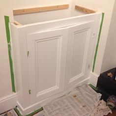 a white door is being installed in a room with green tape on the wall and newspaper