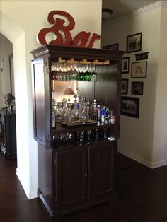 a bar with lots of liquor bottles and glasses on top of it in a living room