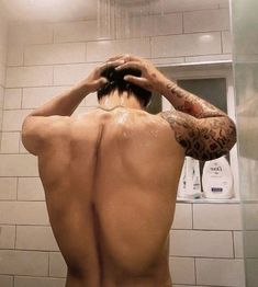 the back of a man who is standing in front of a shower head and arm